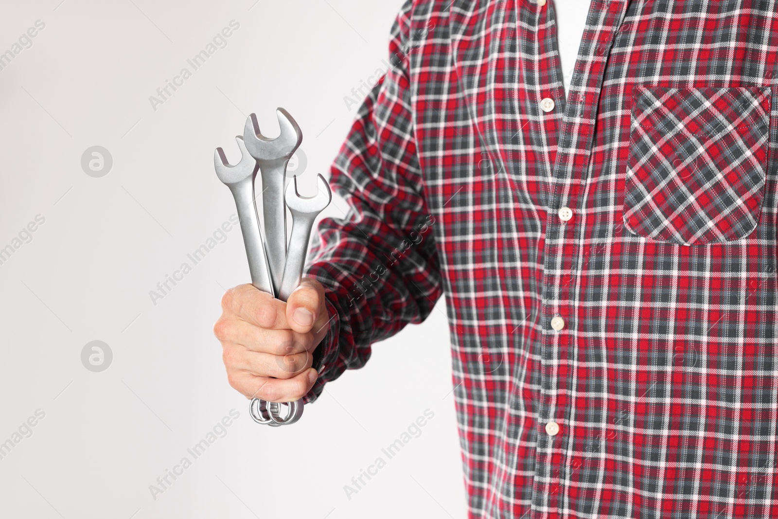 Photo of Auto mechanic with wrenches on light grey background, closeup. Space for text