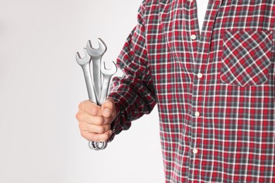 Auto mechanic with wrenches on light grey background, closeup. Space for text