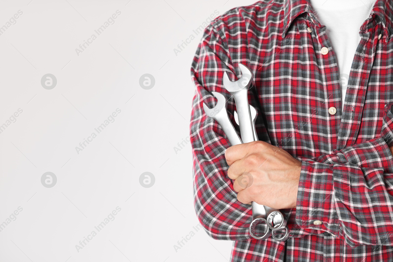 Photo of Auto mechanic with wrenches on light grey background, closeup. Space for text