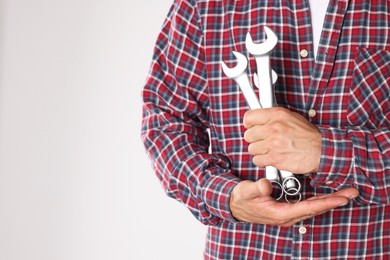 Auto mechanic with wrenches on light grey background, closeup. Space for text