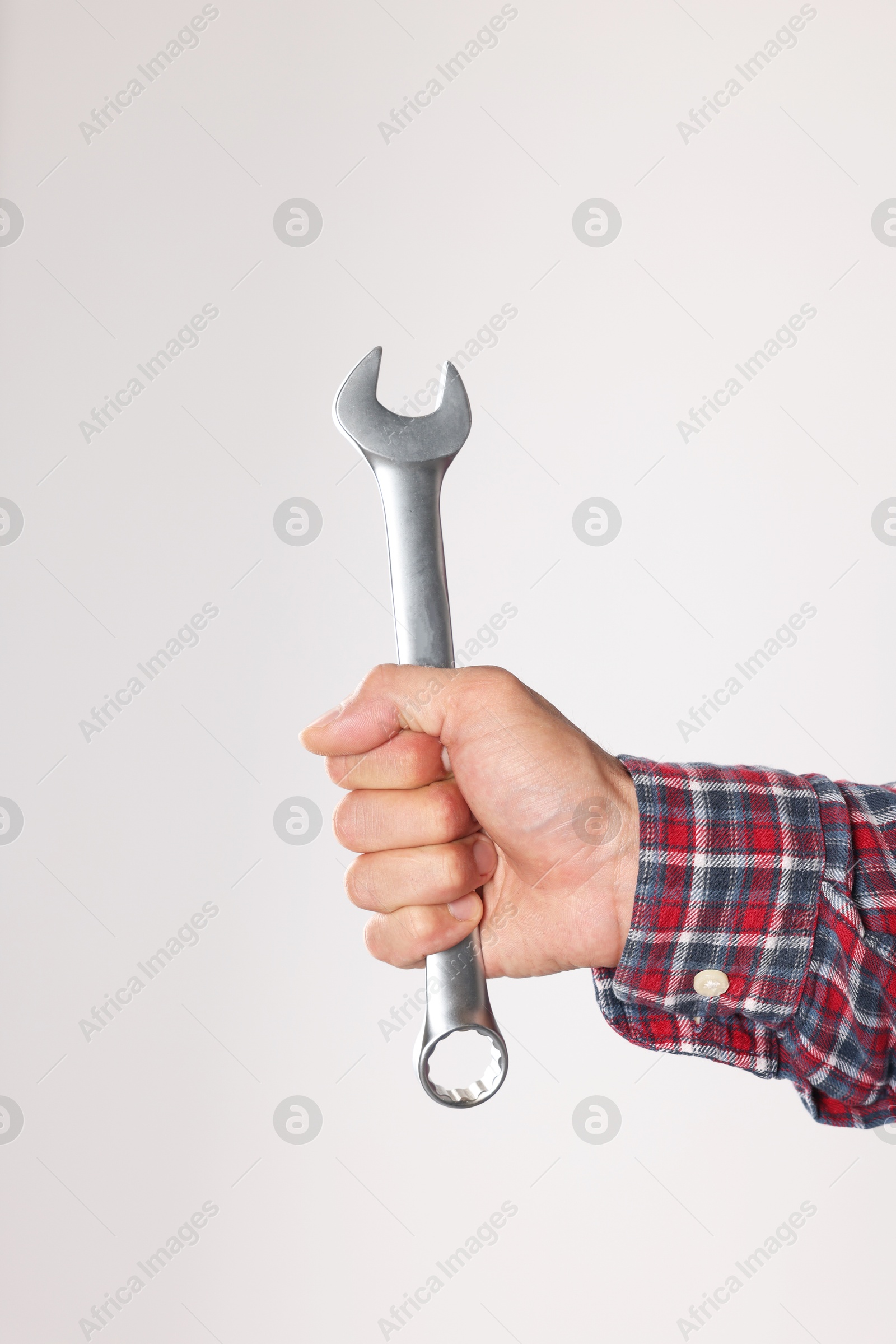 Photo of Auto mechanic with wrench on light grey background, closeup