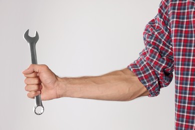 Photo of Auto mechanic with wrench on light grey background, closeup