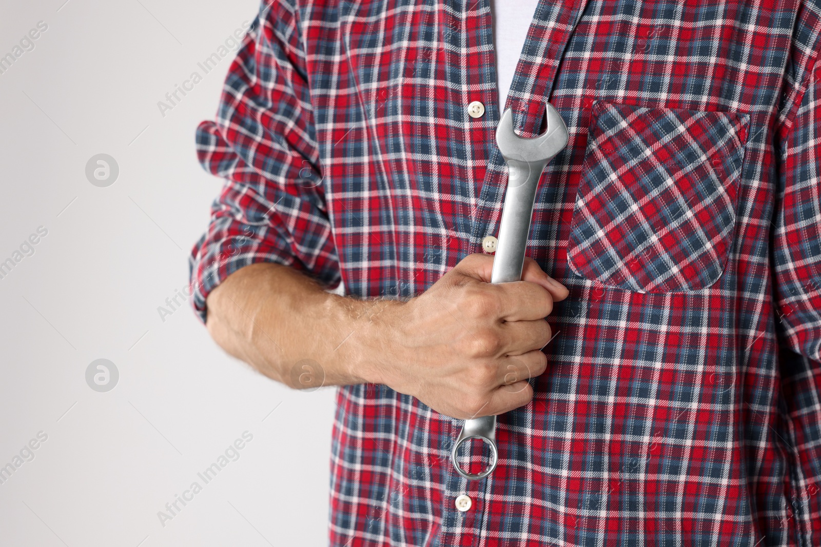 Photo of Auto mechanic with wrench on light grey background, closeup