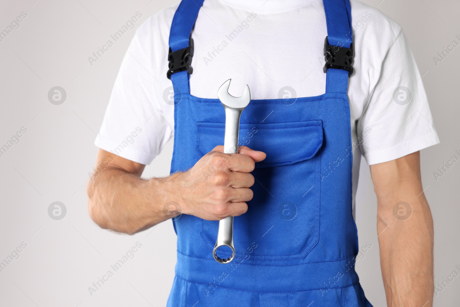 Photo of Auto mechanic with wrench on light grey background, closeup