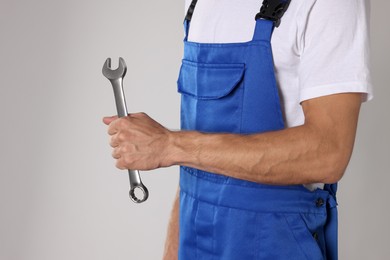 Photo of Auto mechanic with wrench on light grey background, closeup