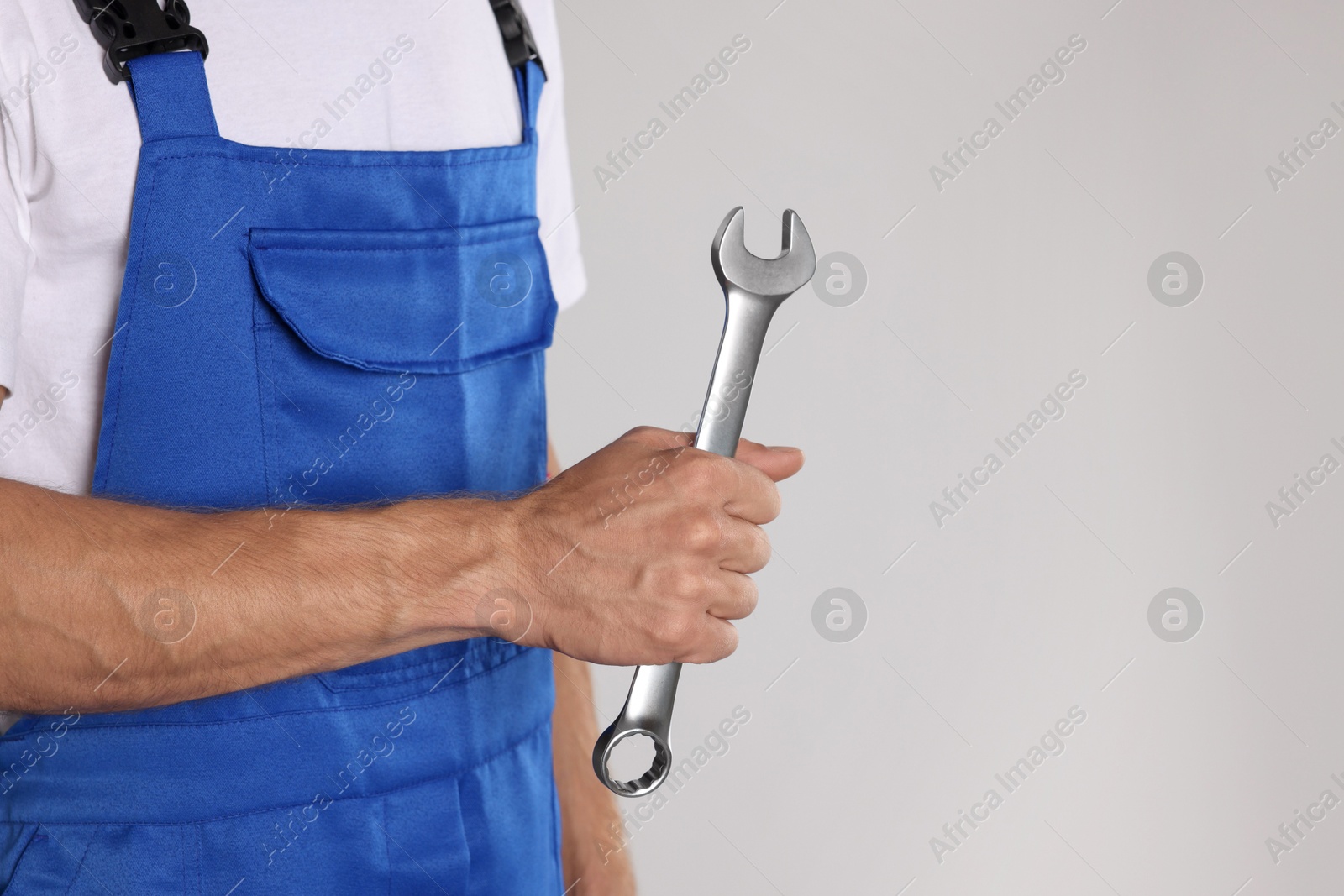 Photo of Auto mechanic with wrench on light grey background, closeup. Space for text