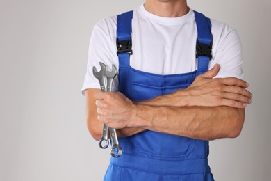 Photo of Auto mechanic with wrenches on light grey background, closeup