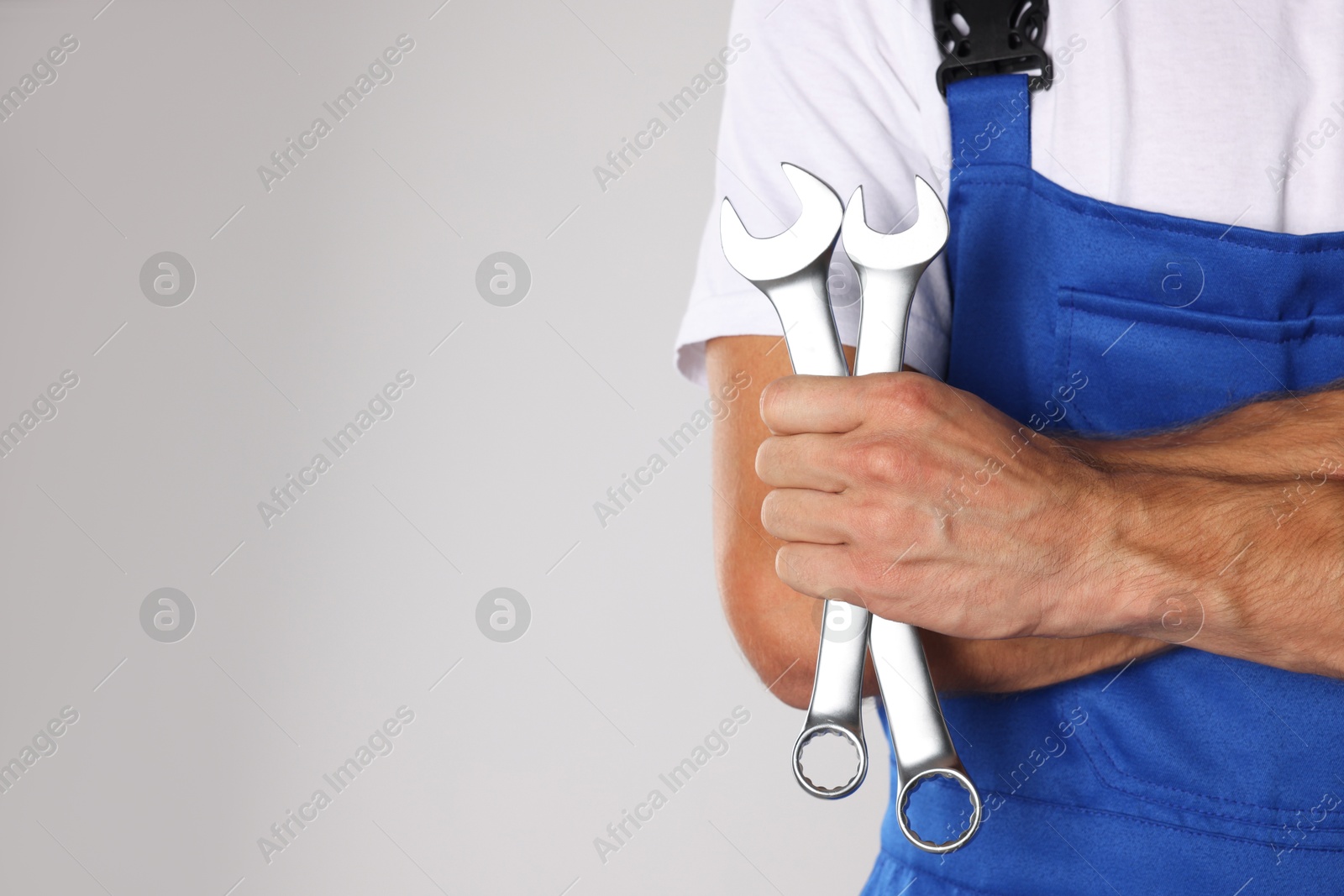 Photo of Auto mechanic with wrenches on light grey background, closeup. Space for text