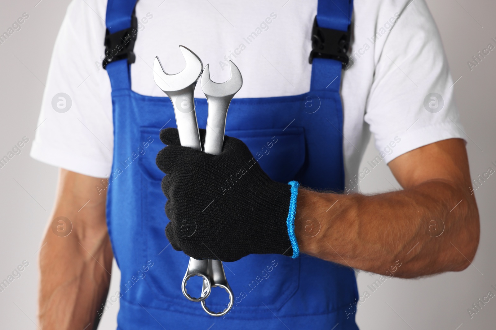 Photo of Auto mechanic with wrenches on light grey background, closeup