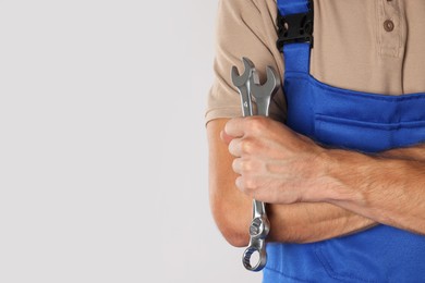 Auto mechanic with wrenches on light grey background, closeup. Space for text