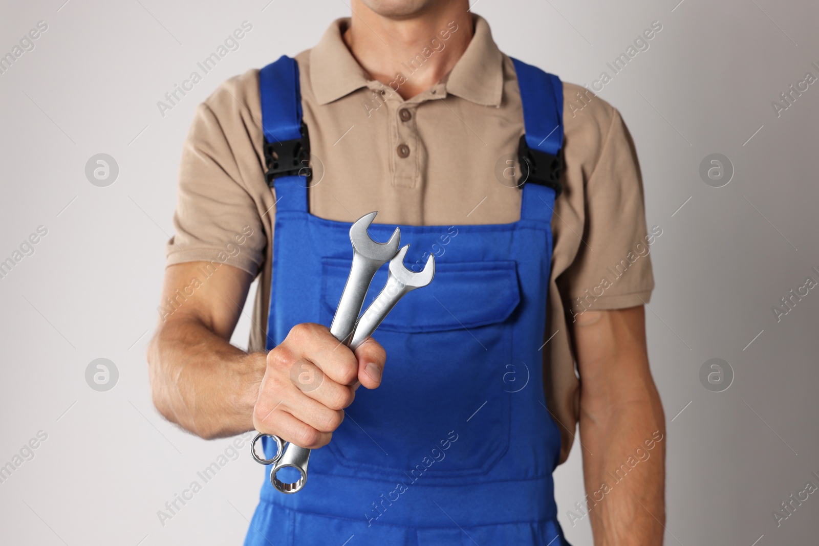 Photo of Auto mechanic with wrenches on light grey background, closeup