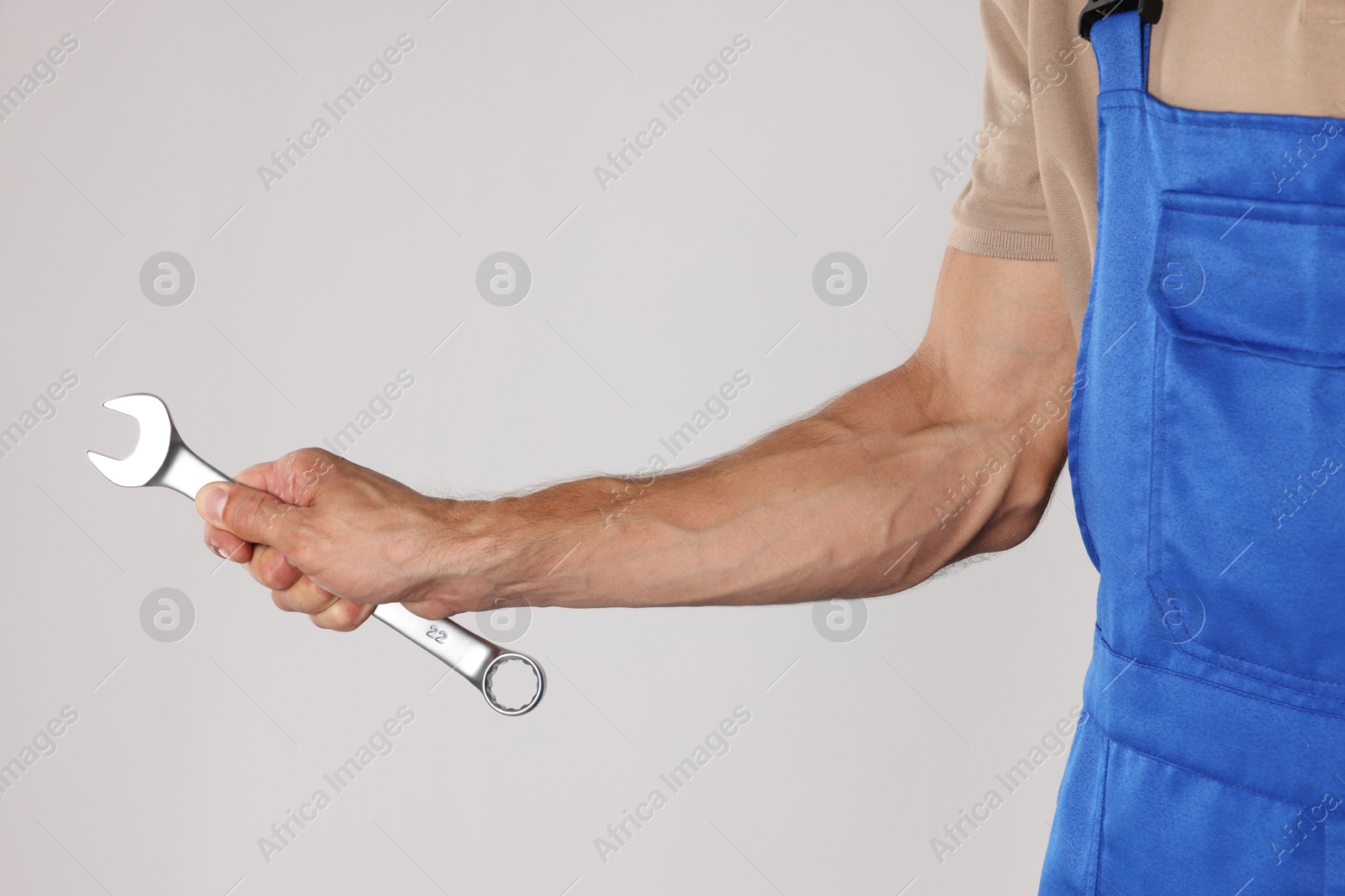 Photo of Auto mechanic with wrench on light grey background, closeup