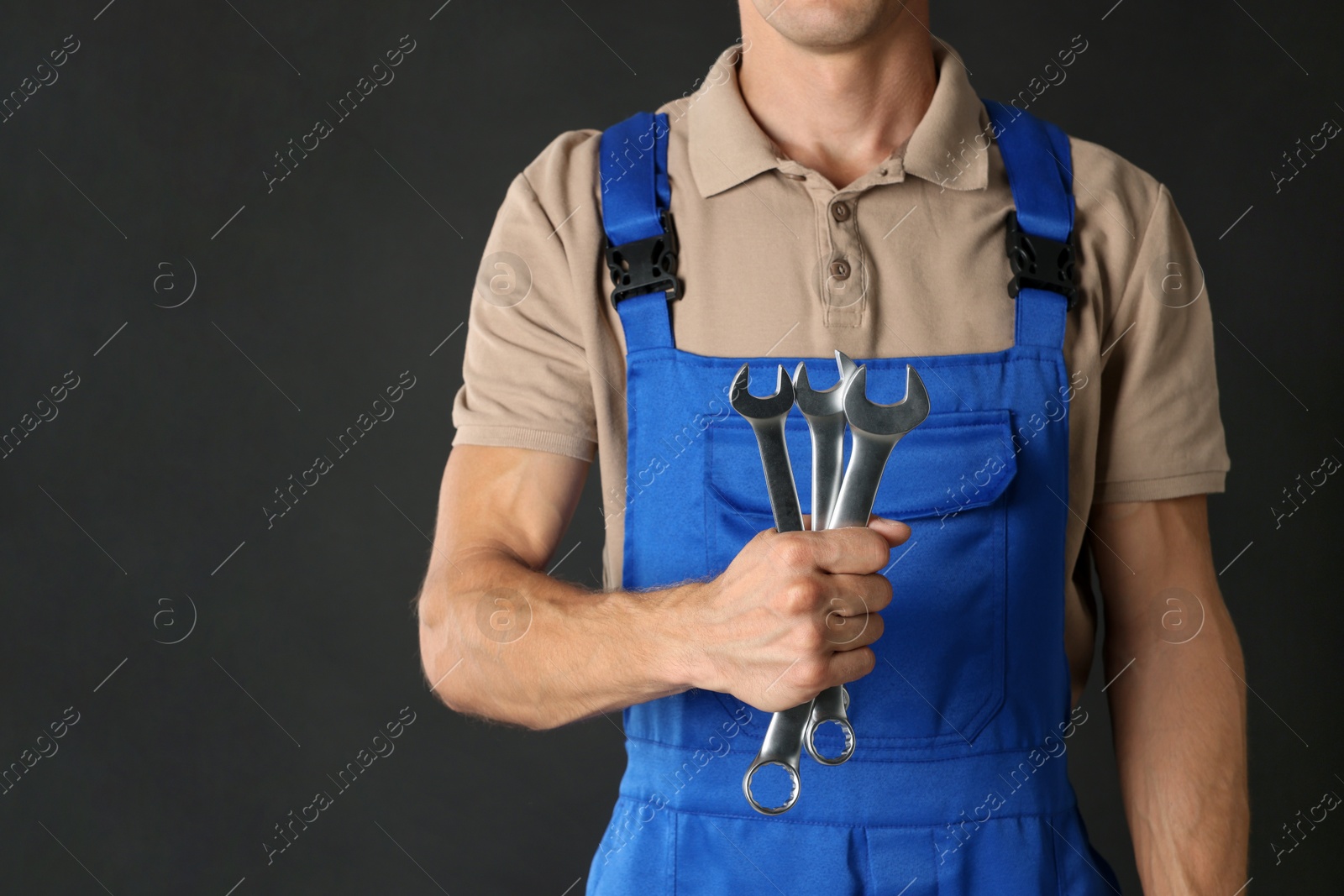 Photo of Auto mechanic with wrenches on black background, closeup. Space for text