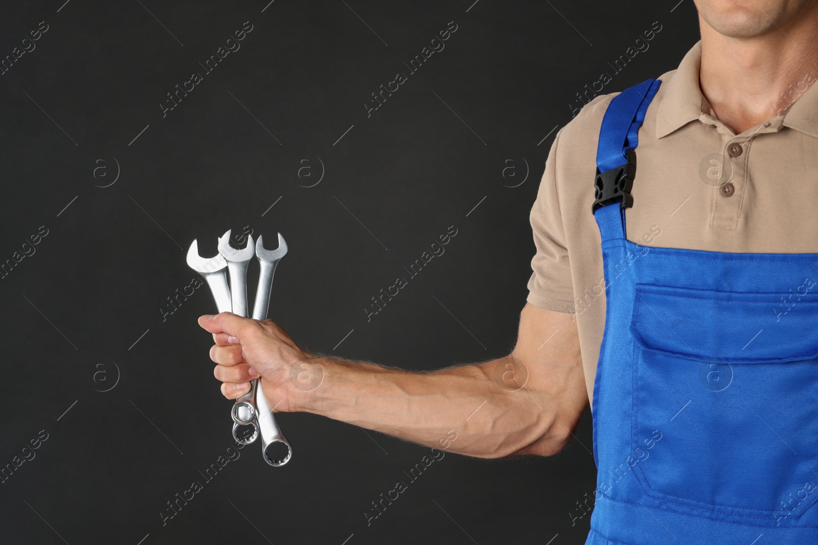 Photo of Auto mechanic with wrenches on black background, closeup