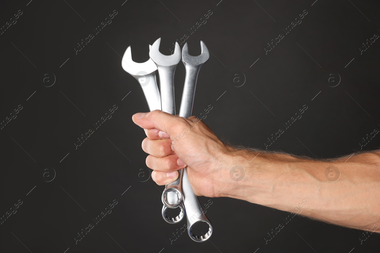 Photo of Auto mechanic with wrenches on black background, closeup