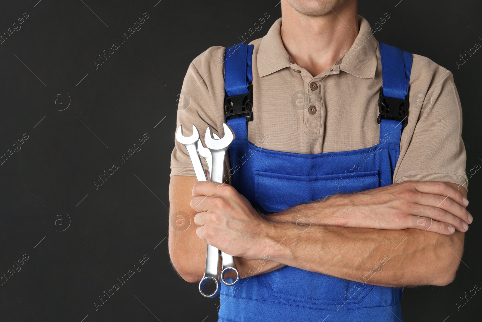 Photo of Auto mechanic with wrenches on black background, closeup. Space for text