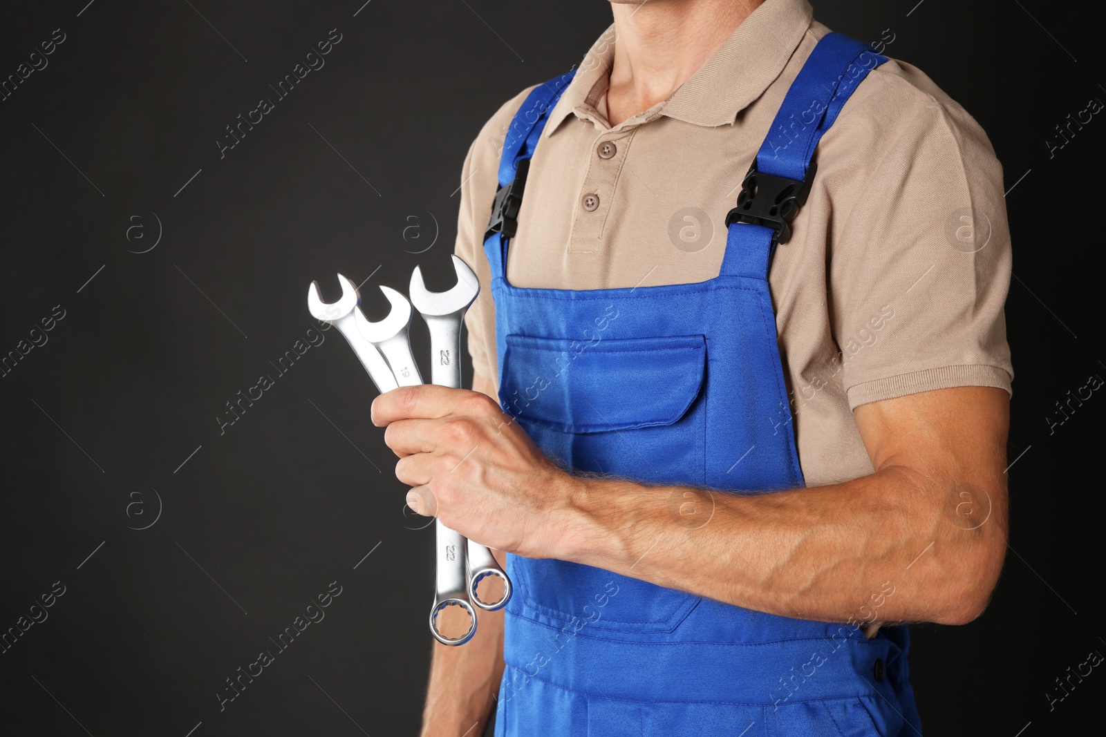 Photo of Auto mechanic with wrenches on black background, closeup. Space for text