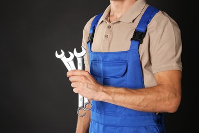 Photo of Auto mechanic with wrenches on black background, closeup. Space for text