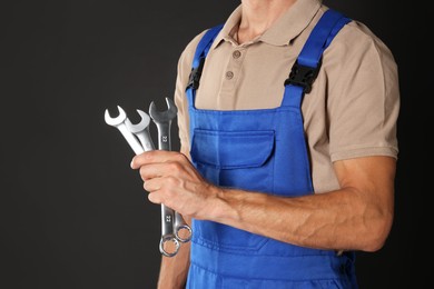 Auto mechanic with wrenches on black background, closeup. Space for text