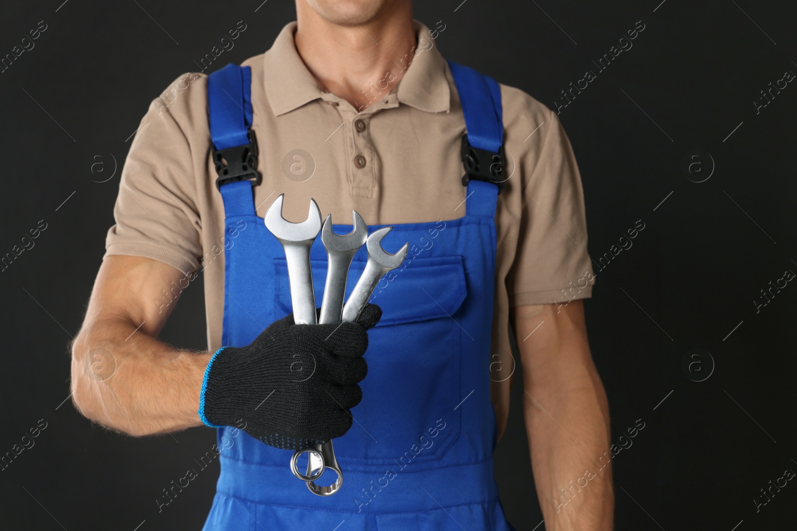 Photo of Auto mechanic with wrenches on black background, closeup