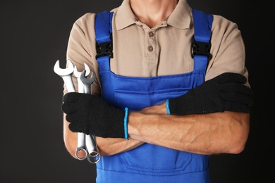 Auto mechanic with wrenches on black background, closeup