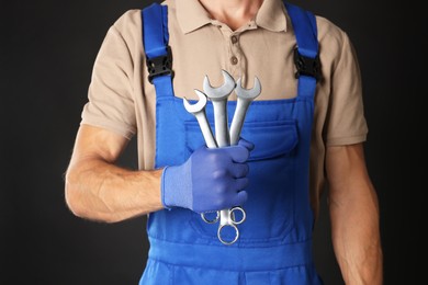 Auto mechanic with wrenches on black background, closeup