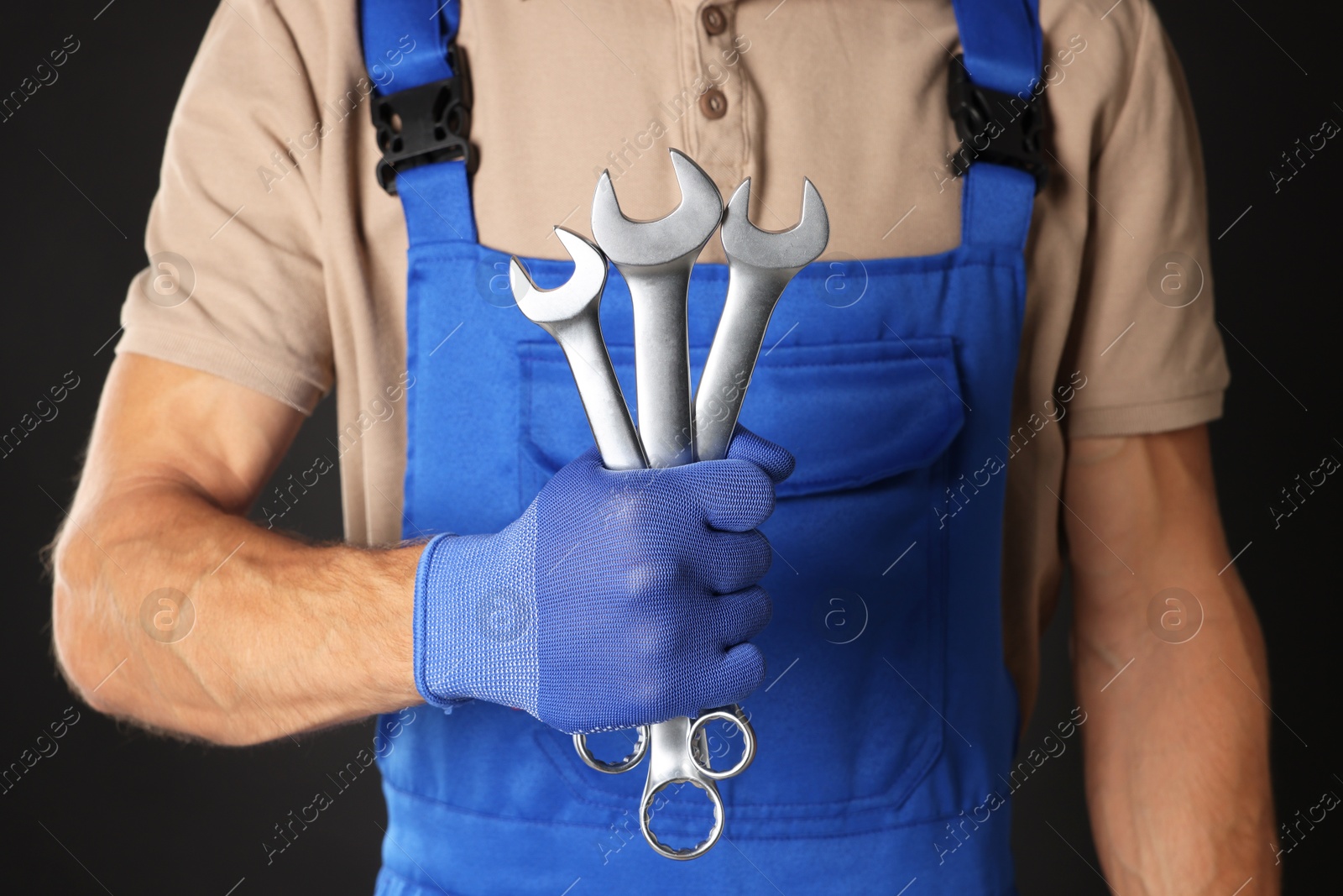 Photo of Auto mechanic with wrenches on black background, closeup