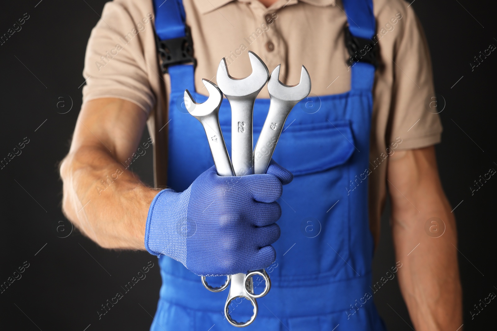 Photo of Auto mechanic with wrenches on black background, closeup