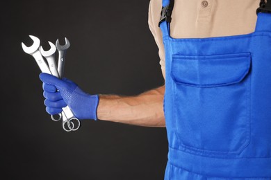 Photo of Auto mechanic with wrenches on black background, closeup