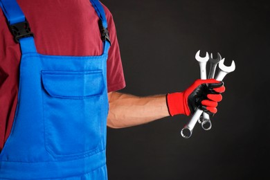 Photo of Auto mechanic with wrenches on black background, closeup