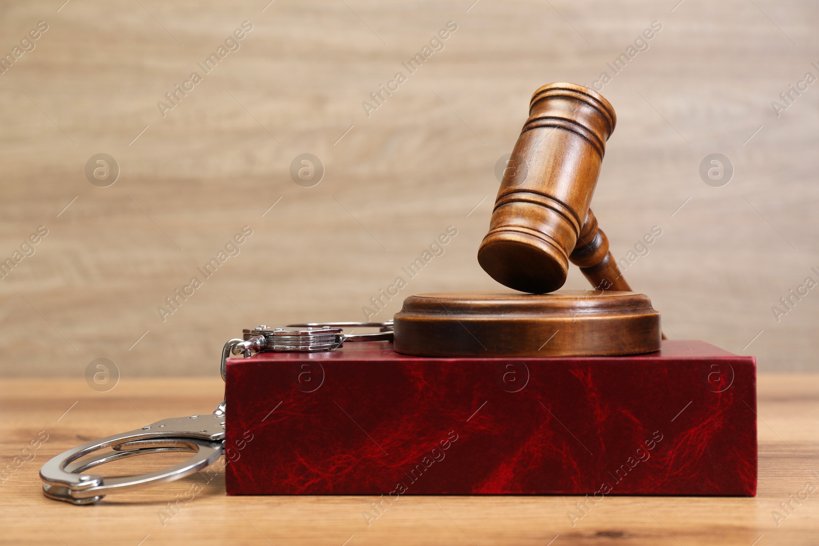 Photo of Book, judge's gavel and handcuffs on wooden table, space for text