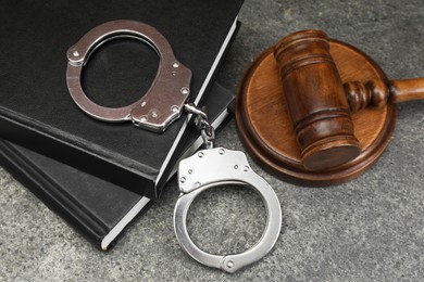 Photo of Books, judge's gavel and handcuffs on gray textured table