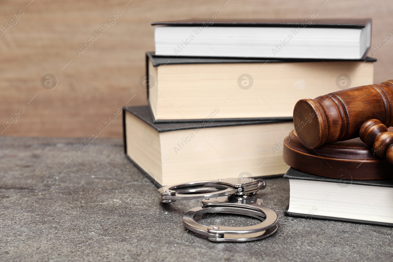 Photo of Books, judge's gavel and handcuffs on gray textured table, closeup