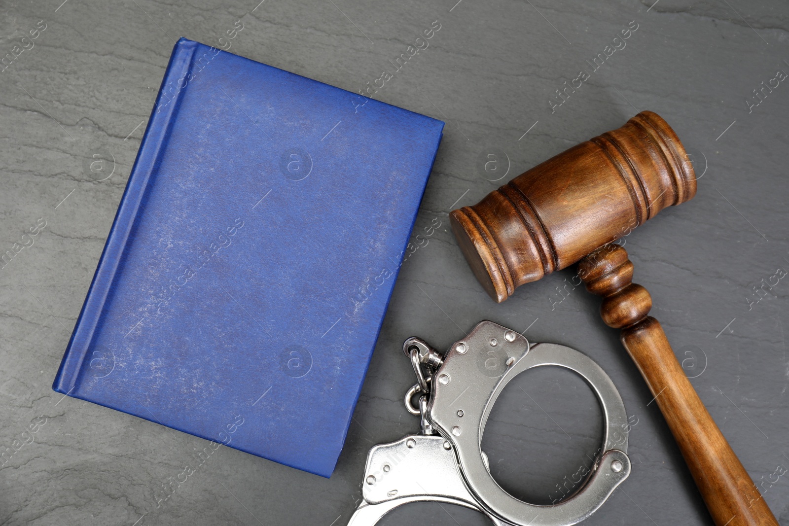 Photo of Book, judge's gavel and handcuffs on gray textured table, flat lay