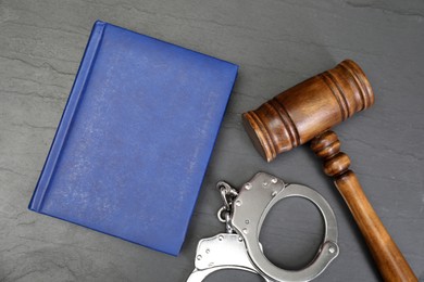 Photo of Book, judge's gavel and handcuffs on gray textured table, flat lay