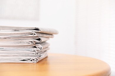 Photo of Stack of many newspapers on wooden table, space for text