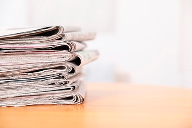 Photo of Stack of many newspapers on wooden table, space for text