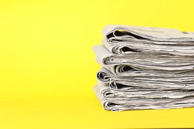 Photo of Stack of newspapers on yellow background, space for text