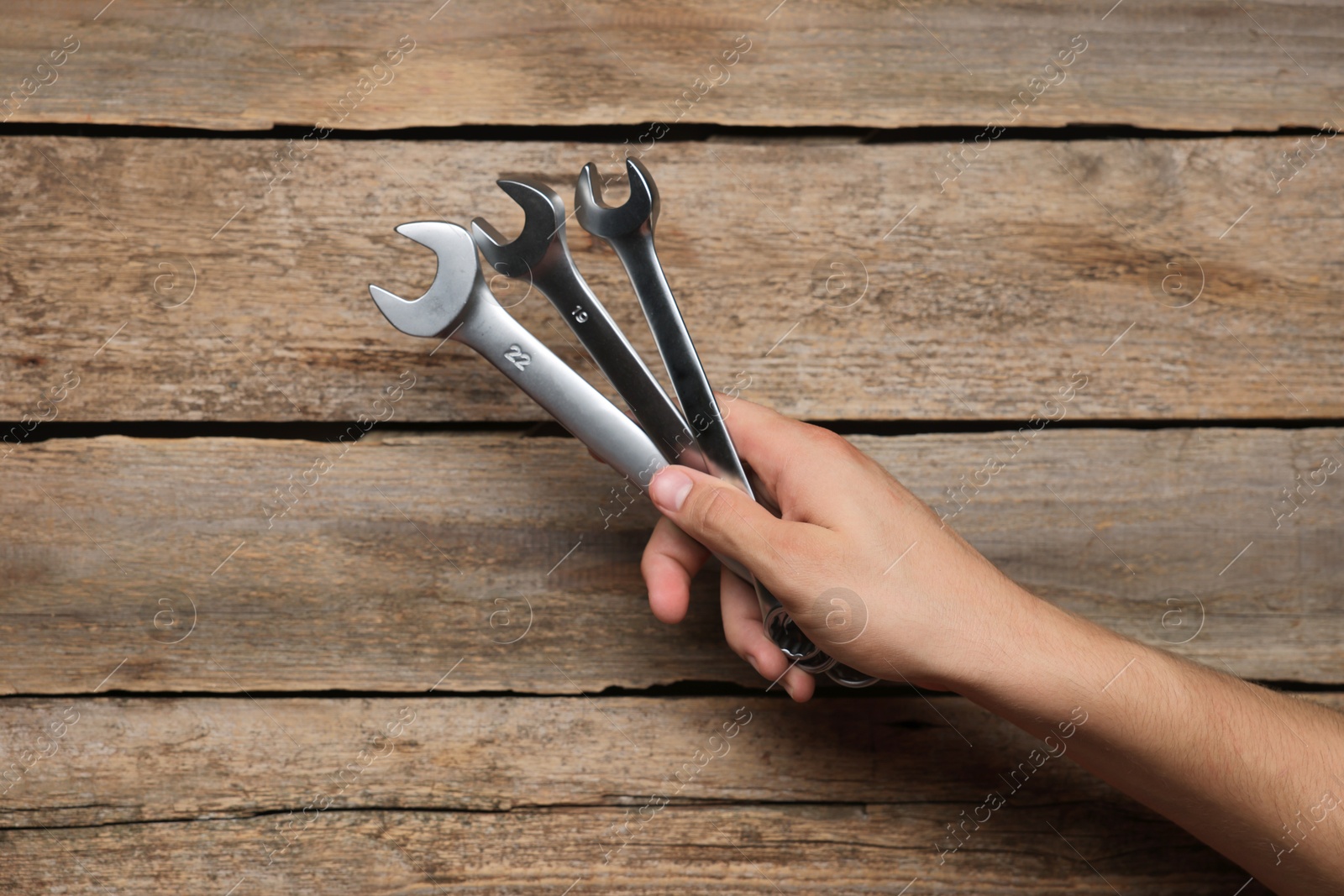 Photo of Auto mechanic with wrenches at wooden table, closeup