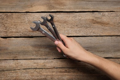 Auto mechanic with wrenches at wooden table, closeup