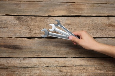 Photo of Auto mechanic with wrenches at wooden table, closeup