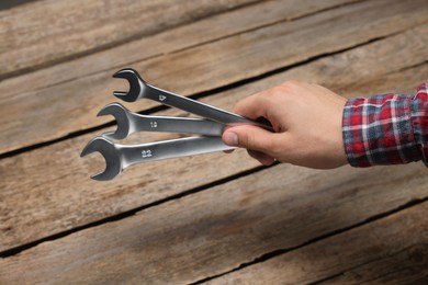 Photo of Auto mechanic with wrenches at wooden table, closeup