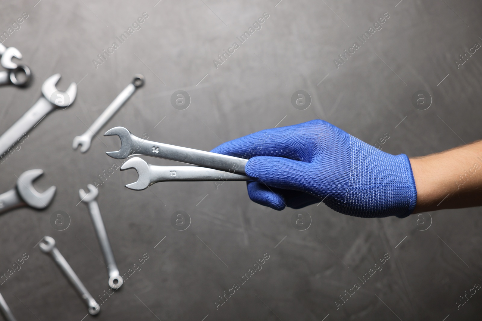 Photo of Auto mechanic with wrenches on grey background, closeup