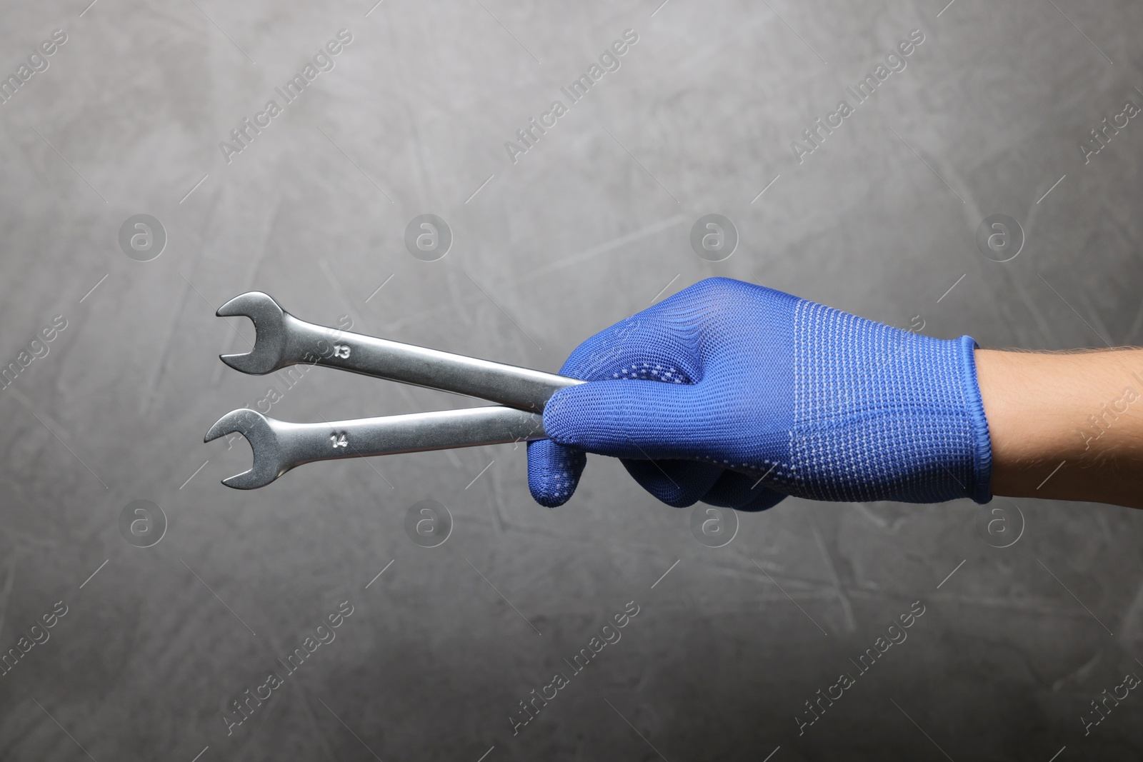 Photo of Auto mechanic with wrenches on grey background, closeup