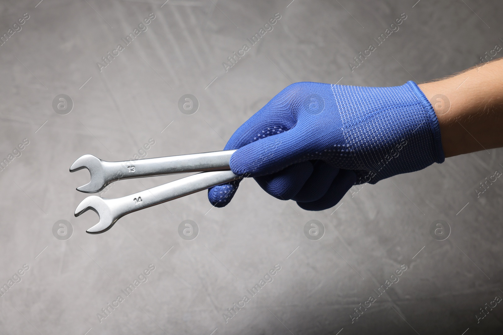 Photo of Auto mechanic with wrenches on grey background, closeup