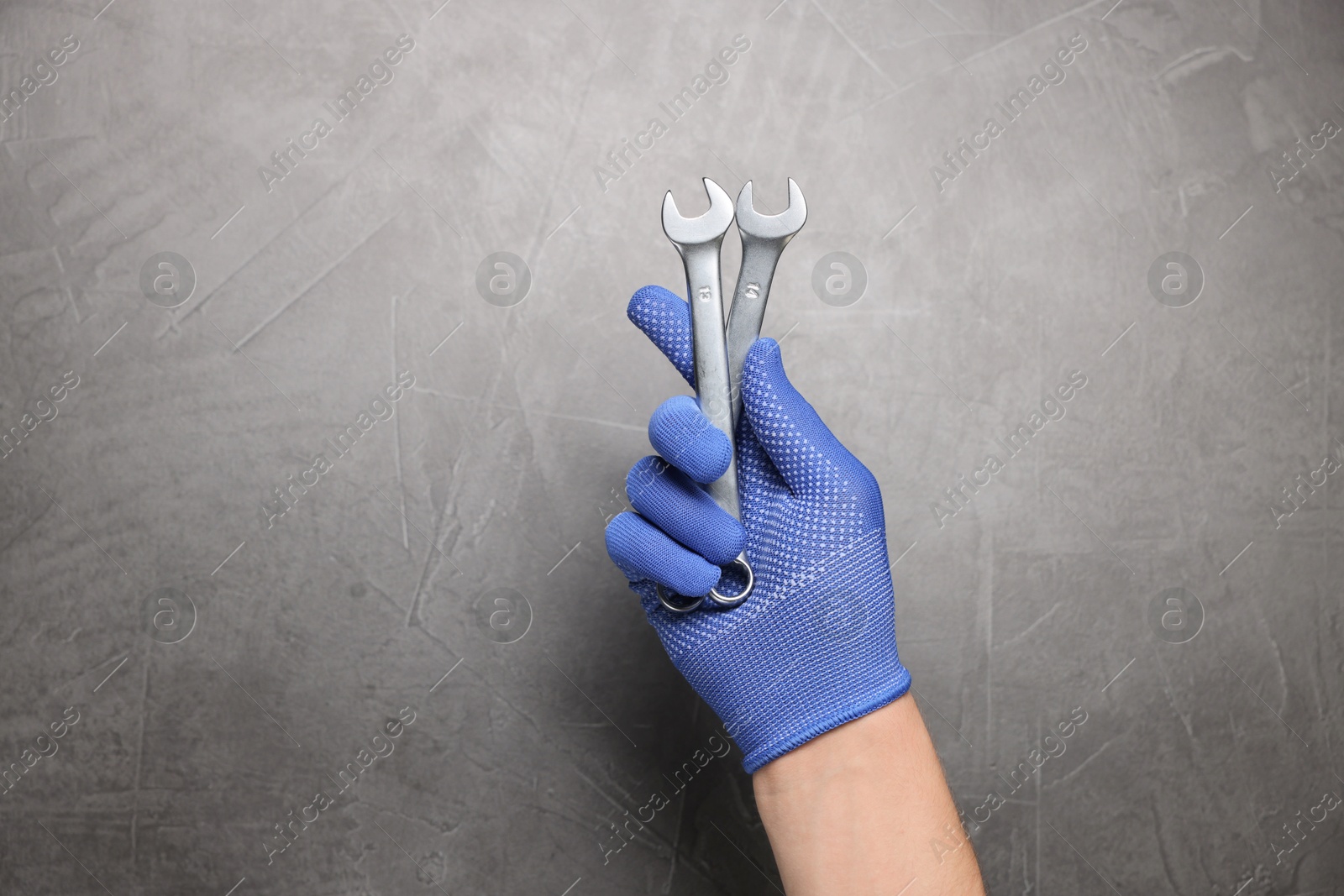 Photo of Auto mechanic with wrenches on grey textured background, closeup