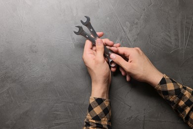 Photo of Auto mechanic with wrenches at grey textured table, closeup