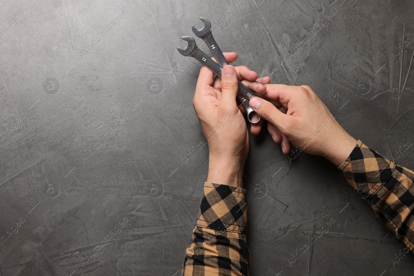 Photo of Auto mechanic with wrenches at grey textured table, closeup. Space for text