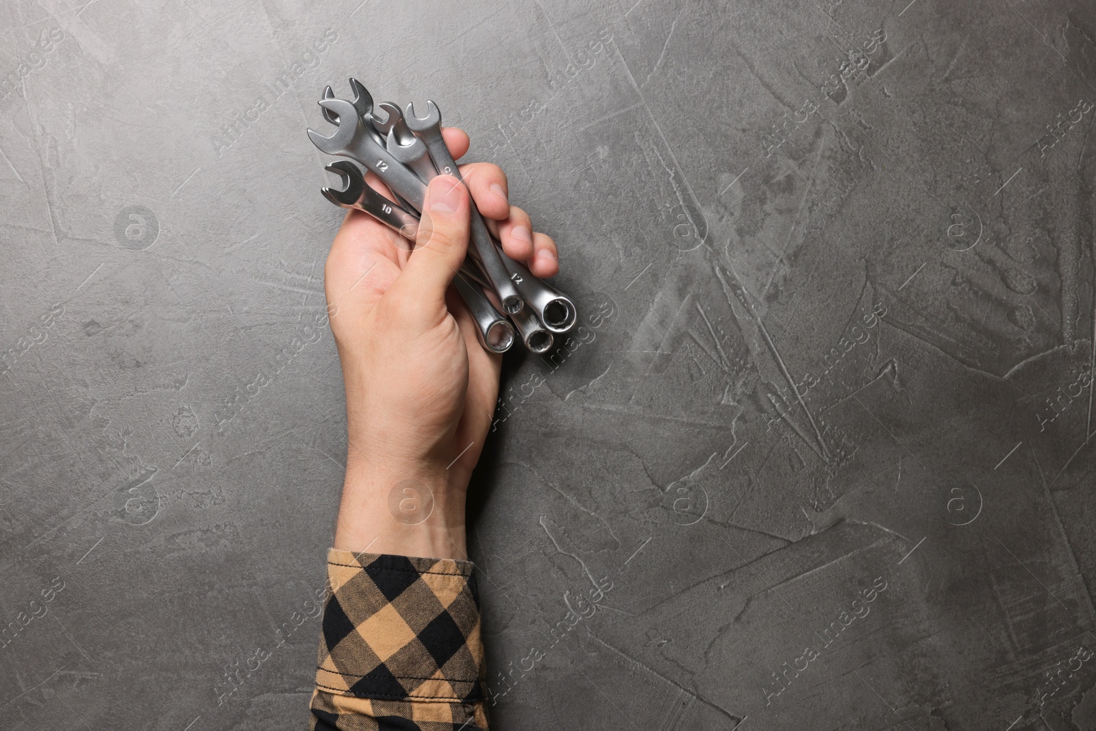 Photo of Auto mechanic with wrenches at grey textured table, closeup. Space for text