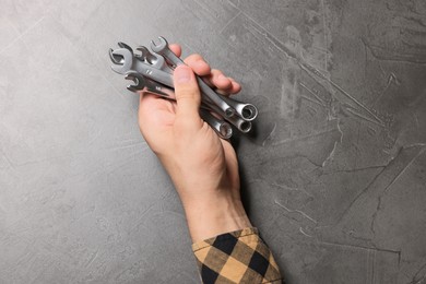 Photo of Auto mechanic with wrenches at grey textured table, top view